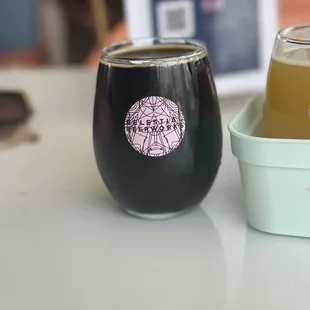 a glass of beer next to a container of liquid