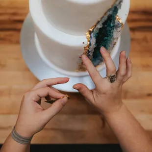 a woman's hands reaching for a slice of the cake