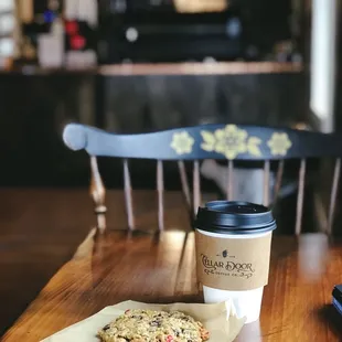a cup of coffee and a cookie on a table