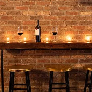 a brick wall with candles and wine glasses