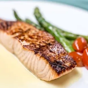 a piece of salmon and asparagus on a white plate
