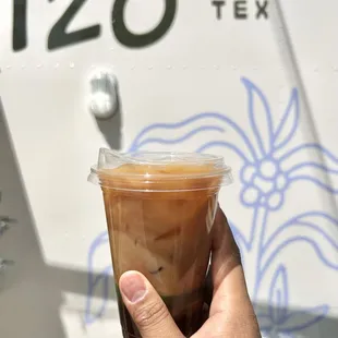 a hand holding a cup of iced coffee