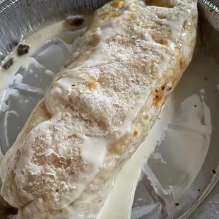 Fajita Burrito  with queso on top. The Burrito got stuck to the lid.