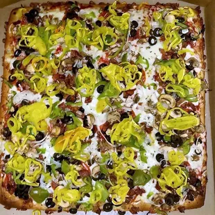 a pizza with olives, peppers, and cheese