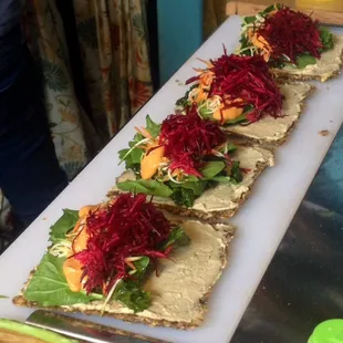Raw veggie sandwiches - beets, zucchini, spinach, kale, hummus, chipotle adobo sauce on onion bread.