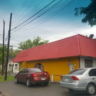 two cars parked in front of a yellow building