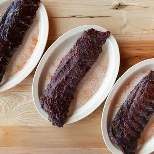 three plates of ribs on a wooden table