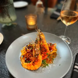Head on pacific prawns  with a local honey &amp; Calabrian Chile sauce served over fried linguine with heirloom tomato gelee .