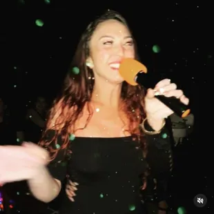 a woman in a black dress eating an orange