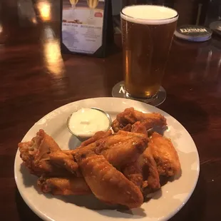 a plate of fried chicken wings and a glass of beer