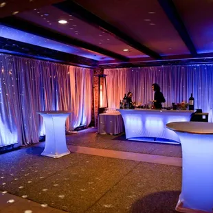 Luxury lounge featuring satin draped walls, up lighting, illuminated bar and cocktail tables. Who's ready for a drink?