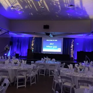 Features draped walls with up lights, gobo lights on the ceiling. Projector screen with sound and complete table settings.