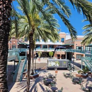 a courtyard with tables and chairs and palm trees