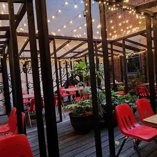 a patio with red chairs and string lights