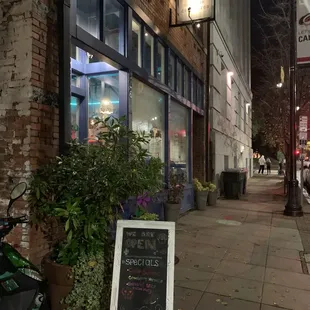 a sidewalk in front of a cafe at night