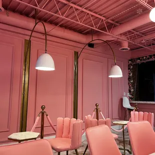 a pink room with chairs and tables