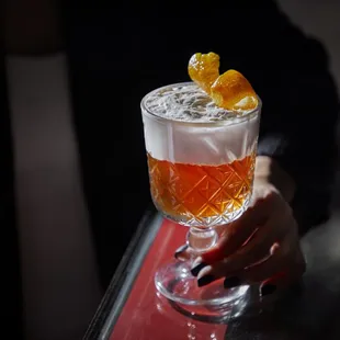 a person holding a glass of cocktail