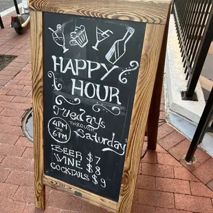 a happy hour sign on a sidewalk