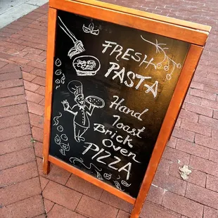 a blackboard sign on a brick sidewalk