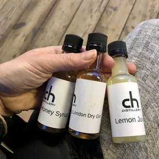 a hand holding three bottles of lemon syrup