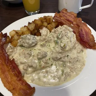 Biscuits and gravy, hash browns with a side of bacon.