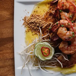 Jumbo shrimp over sautéed glass noodles with tamarind pulp, lime juice, palm sugar, peanuts, organic tofu, sprouts, garlic chives, pickled t