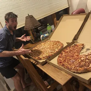 a man standing in front of two pizzas
