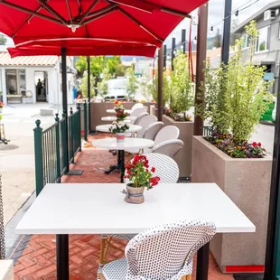 tables and chairs under a red umbrella