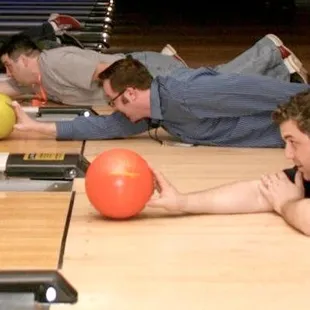 a group of men laying on the floor with bowling balls