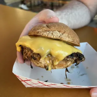 a hand holding a cheeseburger