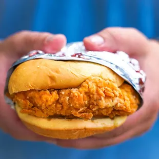 hands holding a sandwich wrapped in foil