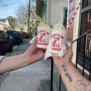 a hand holding two cups of ice cream