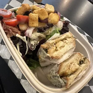a sandwich and salad in a styrofoam container