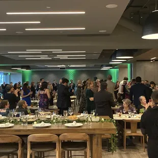 a large group of people standing around a long table