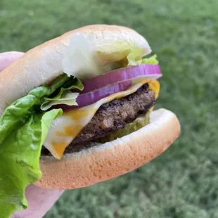 a hand holding a cheeseburger