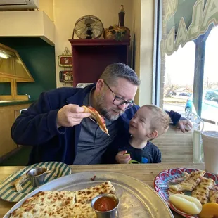 a man and a child eating pizza