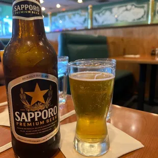 a bottle of sapporo next to a glass of beer