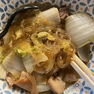 a bowl of soup with chopsticks