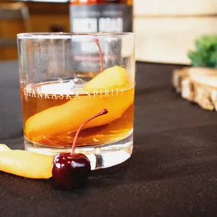 a glass of whiskey with a cherry on the side