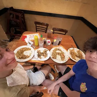 two boys sitting at a table with plates of food