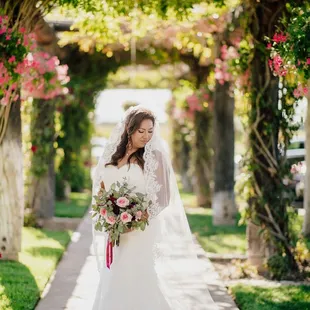 a bride in a wedding dress standing under a pergolated archway