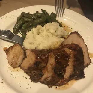 a plate of meat, mashed potatoes, and green beans