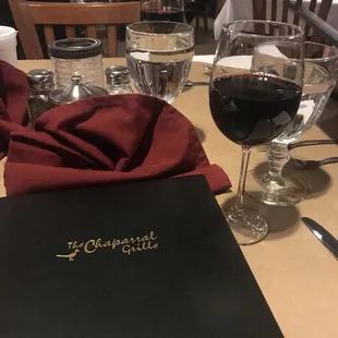 a table with wine glasses and a menu