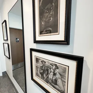 a hallway with framed art and a mirror
