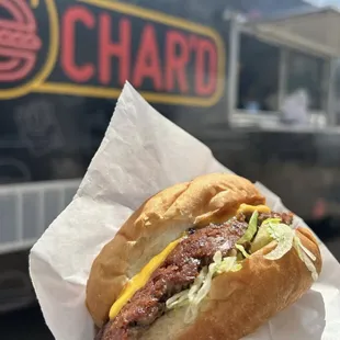 a person holding a sandwich in front of a food truck