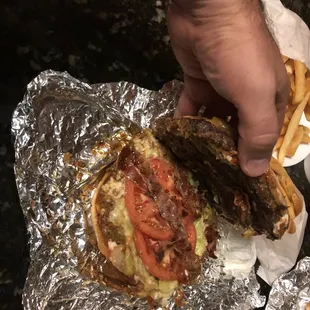 a hand holding a hamburger and french fries