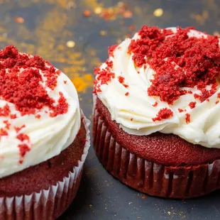 two red velvet cupcakes with white frosting