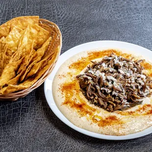 a plate of hummus and a basket of chips