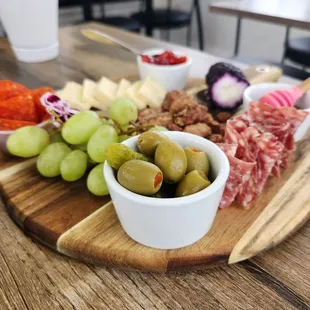 a platter of meat, cheese, olives, and grapes