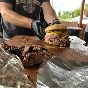 a man preparing a meat sandwich